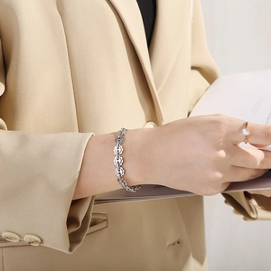 Detail of silver floral hollow link bracelet worn with khaki suit for a modern look