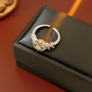 Detail of adjustable flower ring with green oval gemstone and white cubic zirconia