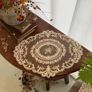 Detailed embroidery of pink roses on beige lace placemat with intricate hollowed edges