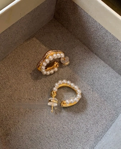 Detail of C-shaped gold hoop earrings with white pearls in a premium jewelry gift box