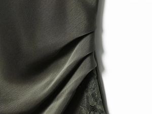 Détail de satin vert olive foncé avec fronces fines et broderie en dentelle florale