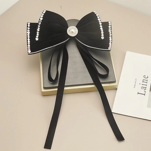 Dettaglio del fiocco per capelli in velluto nero con perla e strass scintillanti
