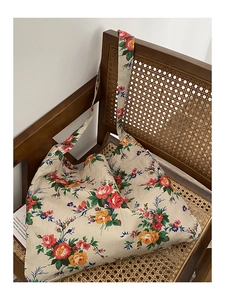 Detail of vintage floral tote bag on woven chair showing thick canvas texture and patterns