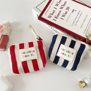 Detailed view of striped canvas makeup bags with embroidery and secure zipper closure