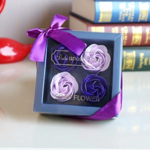 Detail of four purple soap roses in a blue gift box with a purple ribbon bow