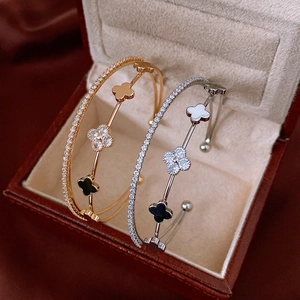 Close-up of gold and silver four-leaf clover open bracelets with cubic zirconia inlays