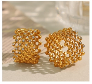Detail view of gold-plated honeycomb mesh rings with embedded Czech diamonds on soft background