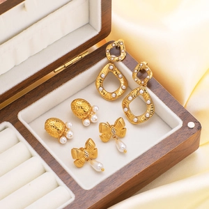 Three-piece gold plated bow and pearl earring set on elegant yellow silk background