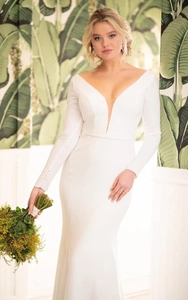 Détail d'une robe de mariée blanche à manches longues avec poignets boutonnés et décolleté en V