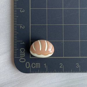 Detailed macro view of a 1.5cm miniature resin croissant accessory on a ruler scale