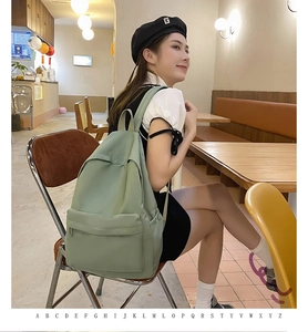 Green nylon backpack shown in a cafe setting with side pockets and front zipper detail
