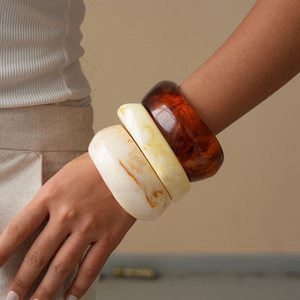Wide resin bangles with geometric marble and tortoiseshell patterns on model's wrist