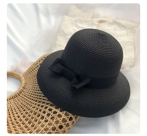 Close-up of black woven straw cloche hat featuring a large elegant grosgrain bow detail