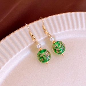 Detail of handmade green glass beads with gold foil foil inside on gold-tone drop earrings