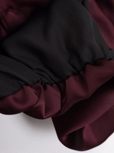 Macro detail of wine red satin fabric with pleated black elastic cuff stitching