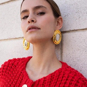 Macro detail of large two-tone gold and silver oval earrings with vintage metal texture