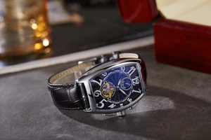 Detailed side view of silver tonneau mechanical watch with blue dial and leather strap