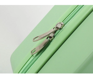Close-up of durable metal dual zippers on light green hard shell mini suitcase