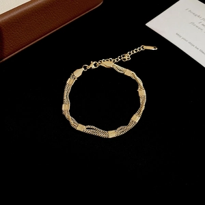 Close-up of golden multi-layer fringe bracelet with metal plates on black velvet