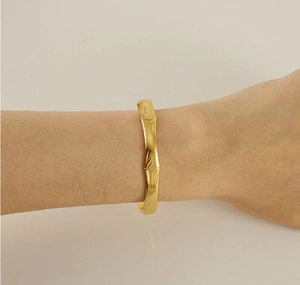 Detailed close-up of a gold bamboo style C-shaped cuff bracelet on a woman wrist