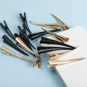Close-up of golden and black eagle beak hair clips on a light blue background