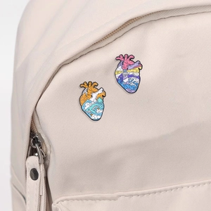 Artistic Van Gogh inspired heart enamel pins set attached to a beige canvas backpack