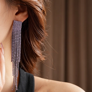 Gros plan de boucles d'oreilles à pompons violets brillants avec strass sur un mannequin