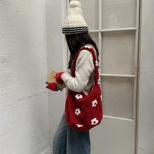 Detail of red knit tote bag with white floral pattern and winter accessories set