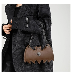 Detail of bat-shaped leather crossbody bag with silver skull ornament and metal chains