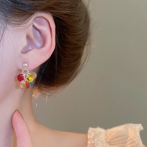 Detail of colorful beaded tassel earrings on model featuring red blue and yellow beads