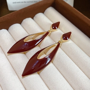 Detail of red enamel water drop earrings with golden edges on a jewelry box background