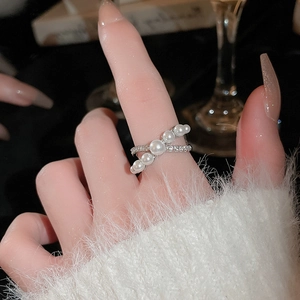 Detailed close-up of a French style pearl and zircon cross ring with elegant gold finish