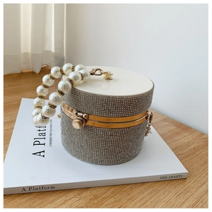Detail of silver rhinestone evening bag with elegant pearl handle on artistic book