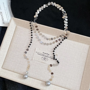 Detail of layered silver sequin chain necklace with black beads and grey pearl drops
