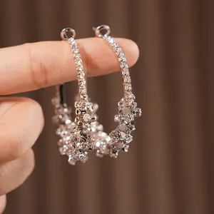 Boucles d'oreilles créoles argentées avec strass présentées sur une main