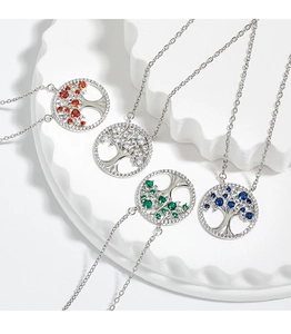 Macro shot of silver tree of life pendants with colorful zircon leaves on white stone
