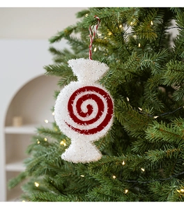 Close-up of a white and red swirl peppermint candy ornament hanging on a Christmas tree