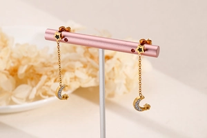Detail of gold moon and star drop earrings with fine chains and zircon accents