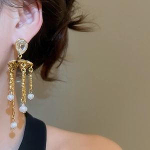 Detail shot of long pearl tassel earrings with gold finish on a model side profile