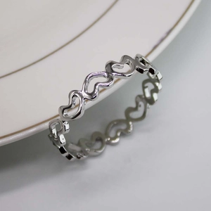 Macro shot of silver hollow heart napkin ring resting on a white ceramic plate edge