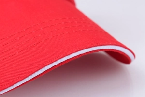 Gros plan sur la casquette en coton rouge avec bord sandwich blanc et détails de couture