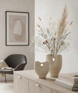 Détail de vases en céramique crème avec texture martelée et design à découpe circulaire