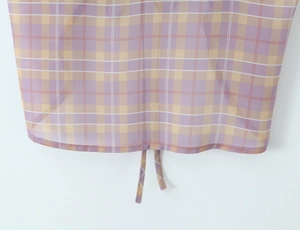 Detail of purple and yellow plaid fabric featuring a ruffled hem and adjustable drawstring