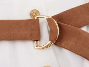 Detail of a brown corduroy belt featuring a gold D-ring buckle and a metallic button finish