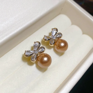 Macro shot of gold bow knot earrings with sparkling rhinestones and golden pearl drops