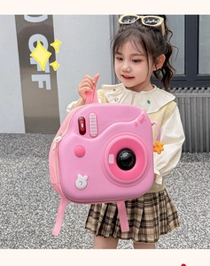 Bambina con zaino rosa a forma di fotocamera rigida in una luminosa strada esterna