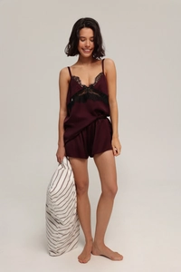 Close-up of burgundy satin pajamas set with delicate black lace trim on the V-neckline