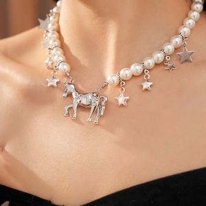 Detailed close-up of pearl necklace featuring a silver horse charm and star pendants
