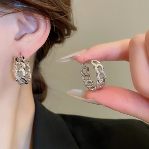 Detailed view of silver interlocking chain earrings with cubic zirconia on model ear