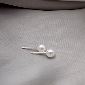 Macro detail of S925 sterling silver stamp on minimalist white pearl stud earrings
